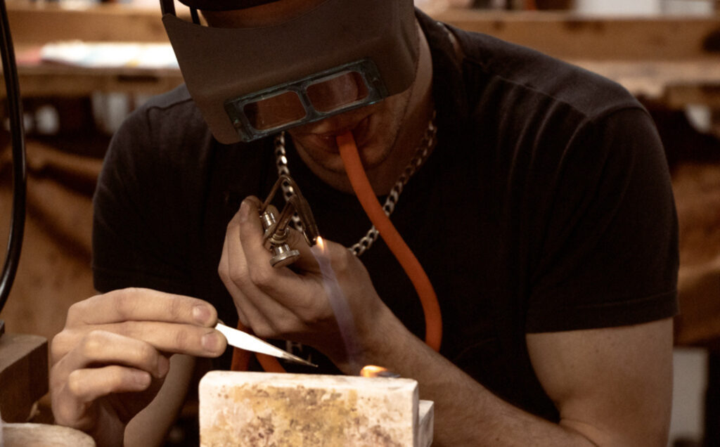 Student using blow torch and tweezers at the workbench